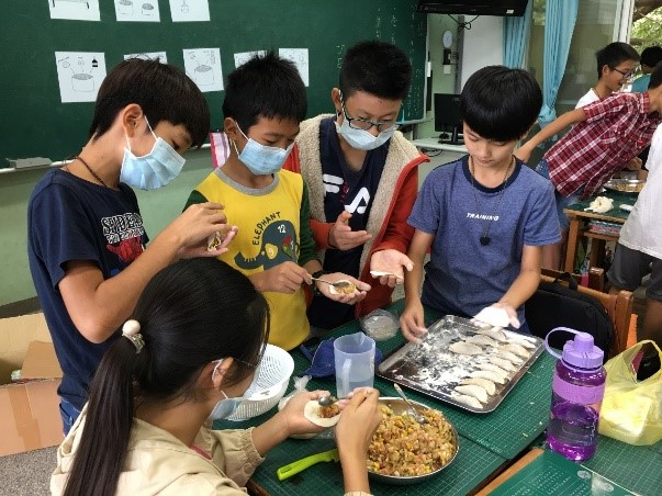 國小學生先是透過紙本教材及平板遊戲學習煮義大利麵和包水餃的知識,接著做中學,最後在課堂上做出美味的義大利麵和水餃